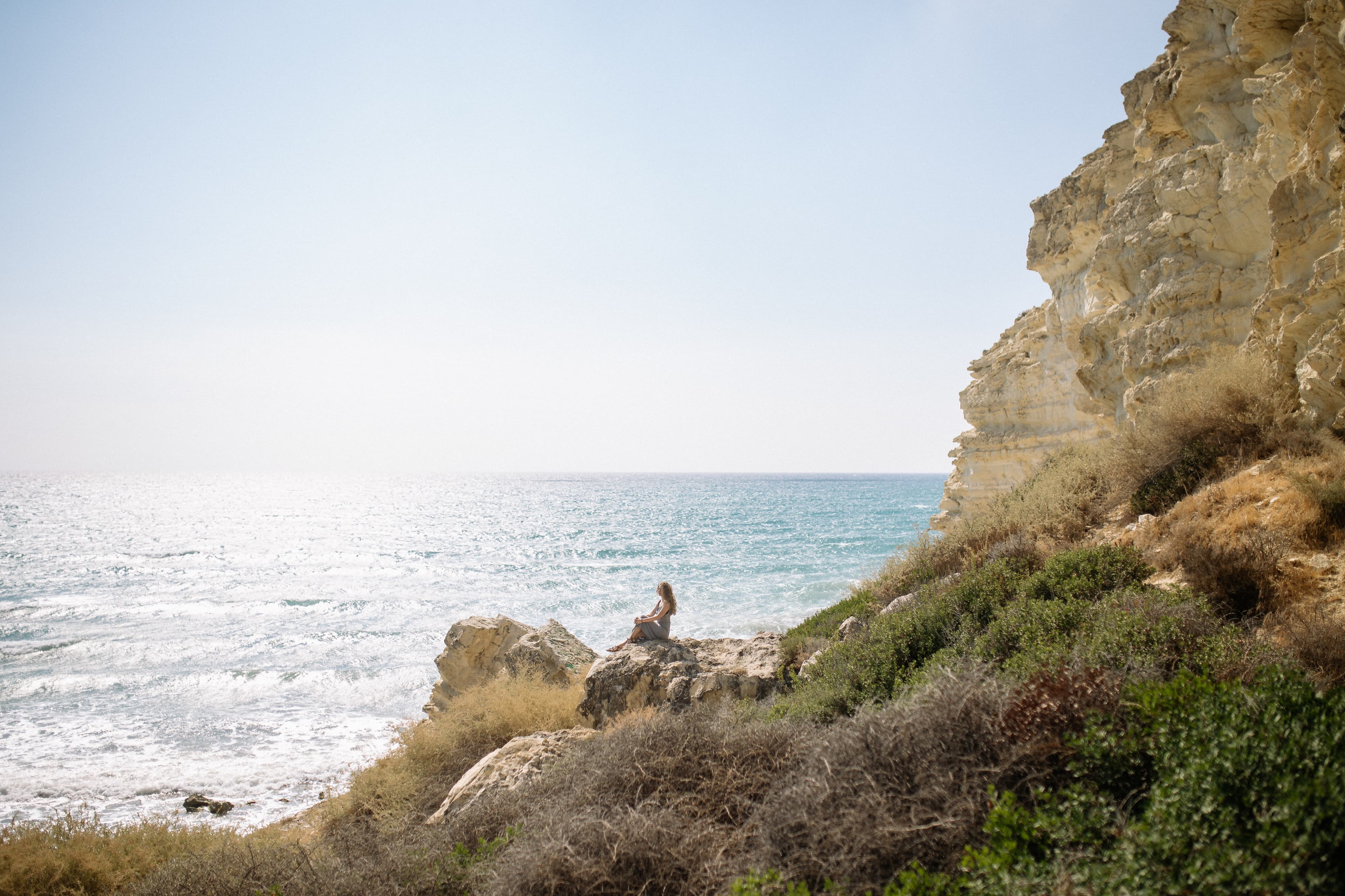 Woman sitting on a rock looking out on the ocean
